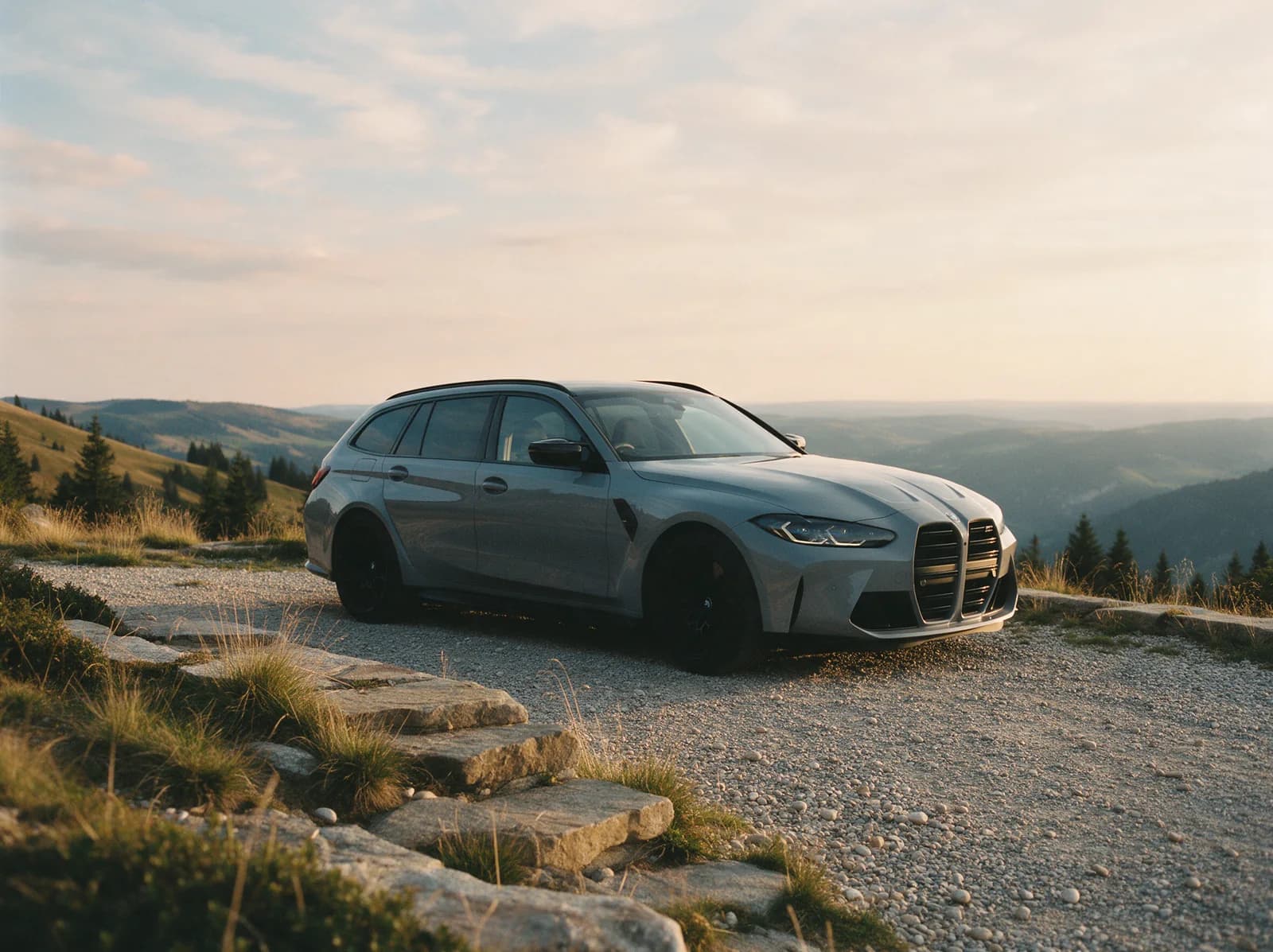 A grey BMW M4 Touring wagon on a mountain road with a ridge line behind