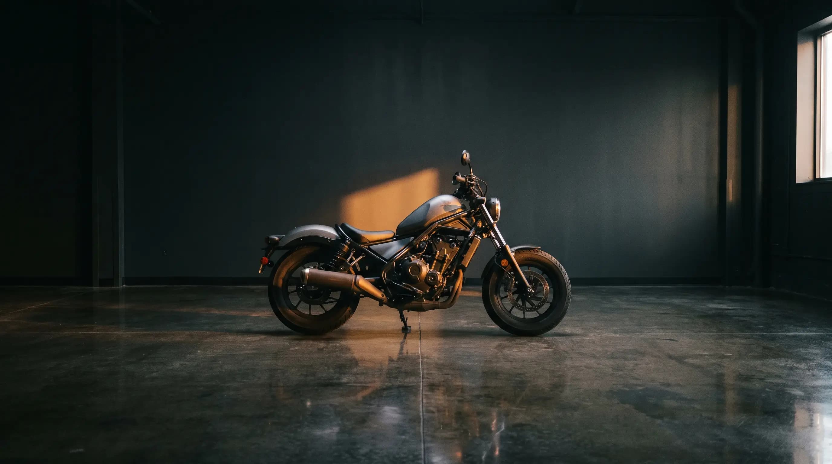 Motorcycle standing in a dark showroom under a single warm key light